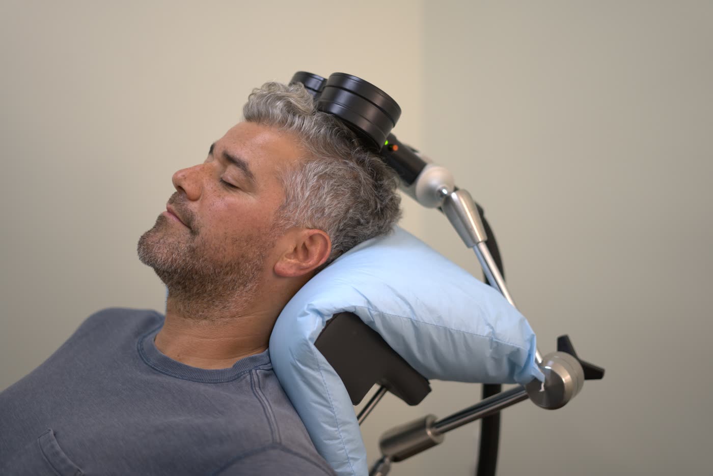 A patient relaxed in a chair receiving personalized TMS treatment